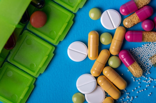 Top view with a green organizer from which he poured pills and multicolored capsules. Green and white colors