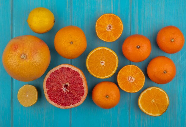 Top view with slices and whole orange and grapefruit on turquoise background