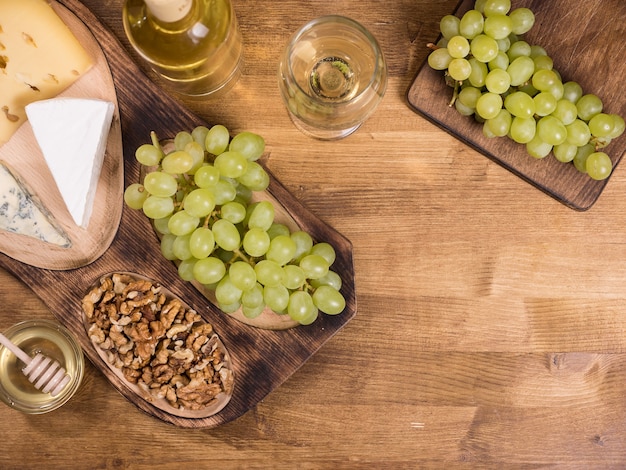 Free photo top view of wolnuts next to fresh grapes on wooden plate in a vintage restaurant. glas of white wine.