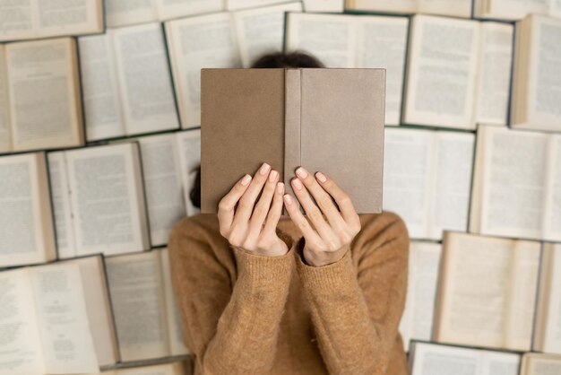 Top view a woman in a cozy soft sweater lies on open books