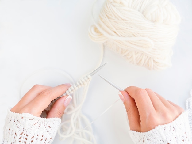 Top view of woman crocheting with white wool