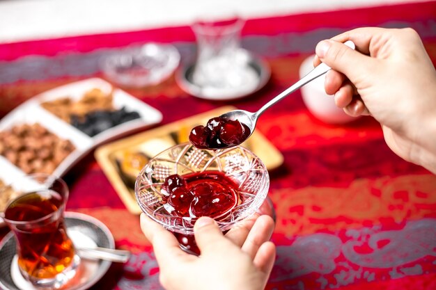 Top view woman eats cherry jam with tea