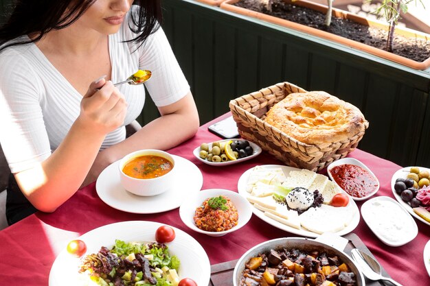 Top view woman eats chicken soup with salads and cheese