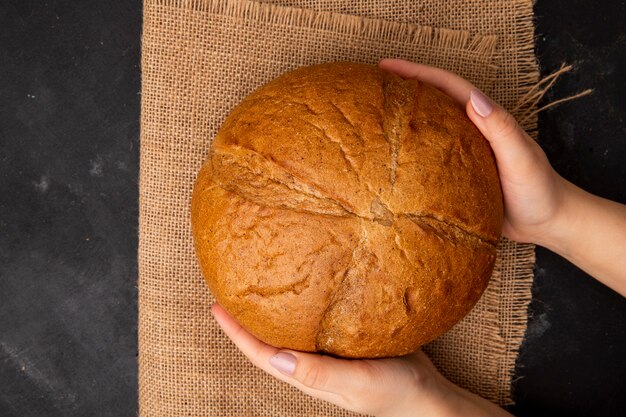 Top view of woman hands holding classic cob on sackcloth on black background