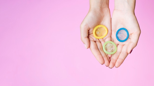 Free photo top view woman holding colourful condoms