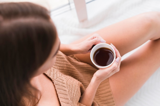 Free photo top view woman holding a cup of coffee