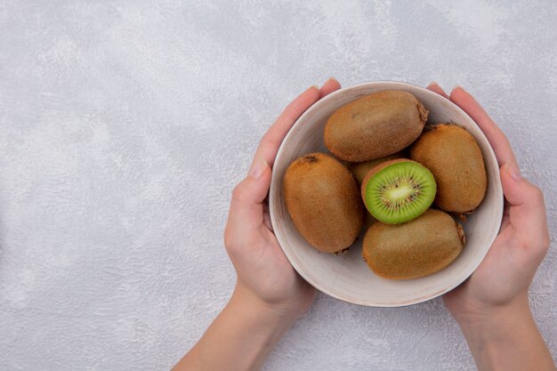 Top view  woman holding kiwi in a bowl on white background