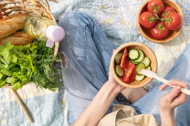 Top view woman holding salad bowl at picnic