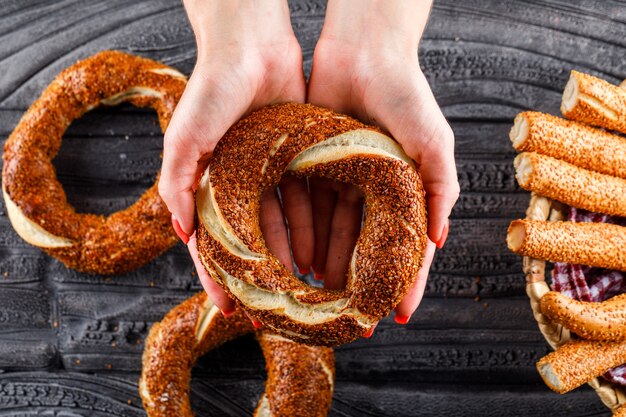 Top view woman holding turkish bagel on dark wooden surface. horizontal