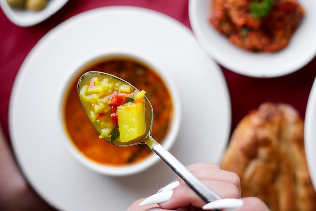 Vista dall'alto una donna tiene un cucchiaio con brodo di pollo con pane