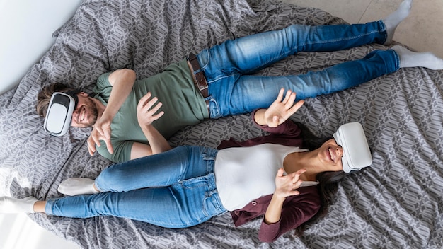 Top view of woman and man using virtual reality headset in bed