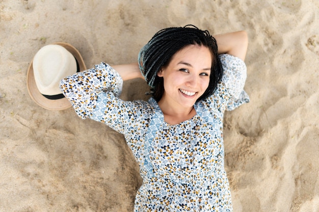 Foto gratuita donna di vista superiore che posa sulla spiaggia