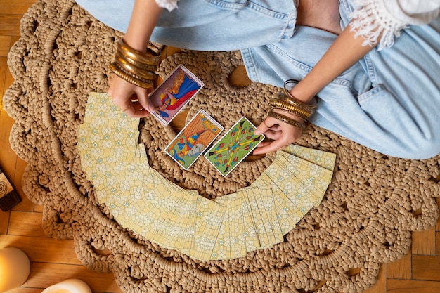 Free photo top view woman reading tarot at home