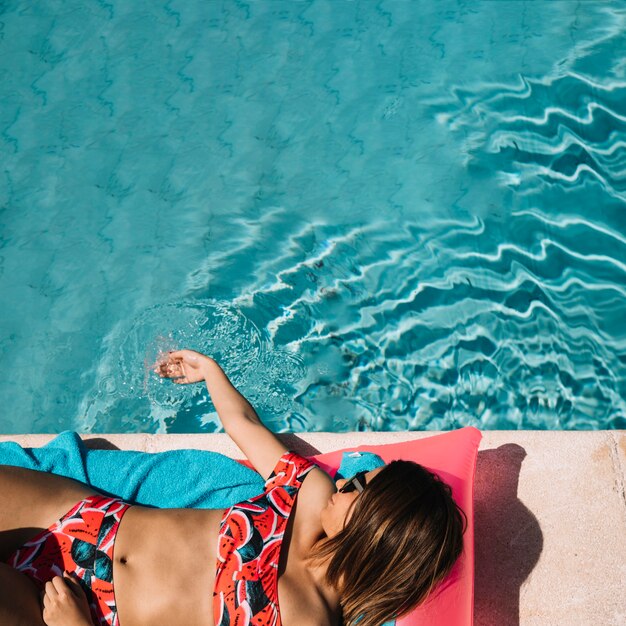 Вид сверху на женщину, расслабляющую рядом с бассейном