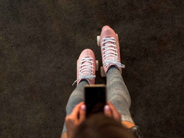 Top view of woman in roller skates holding smartphone