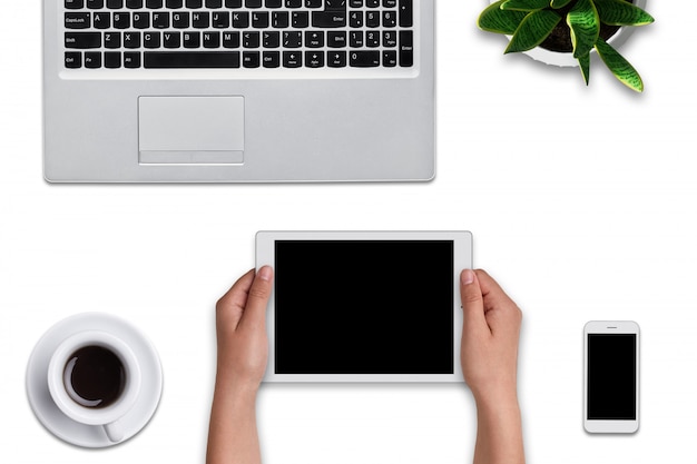 Top view of woman`s hands holding modern tablet with blank screen. Laptop computer, smart phone, tablet