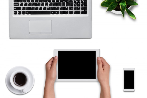 空白の画面を持つ近代的なタブレットを保持している女性の手の平面図です。ラップトップコンピューター、スマートフォン、タブレット
