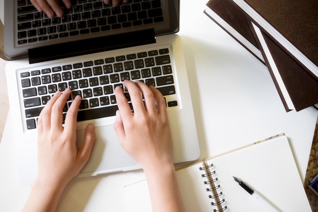 Top view of woman's hands working with laptop.