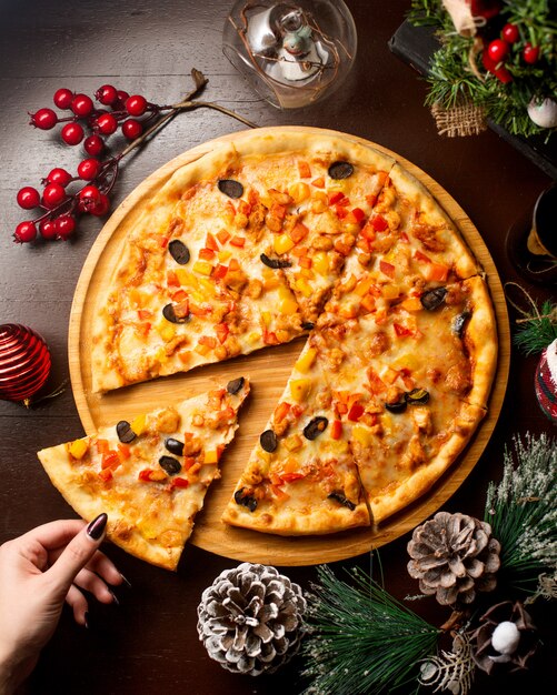 Free photo top view of woman taking a slice off chicken pizza