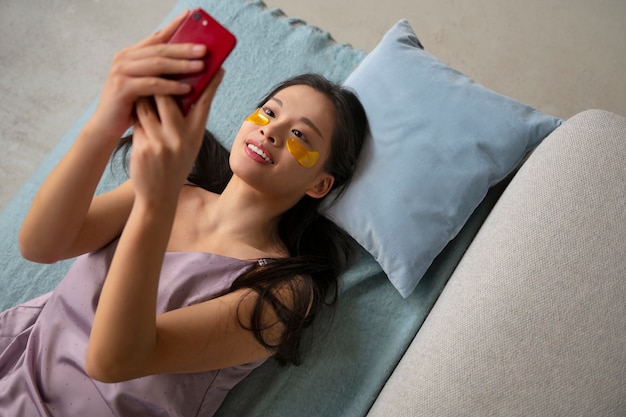 Free photo top view woman using eye patches