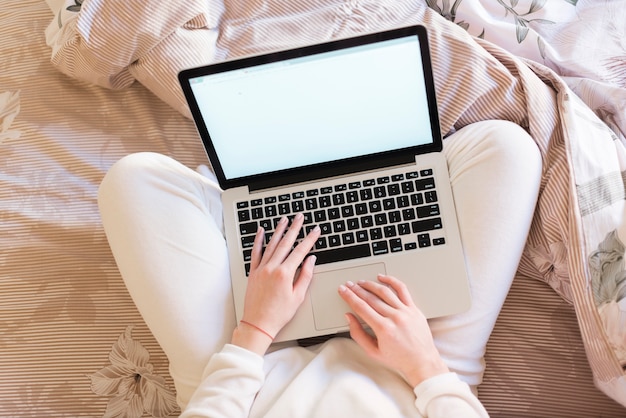 Top view of woman with laptop on the bed