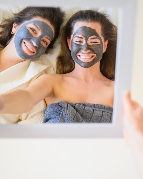 Top view of women with face masks looking in the mirror