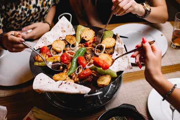 Top view womens eat a traditional azerbaijani dish chicken sage with vegetables potatoes and pita bread