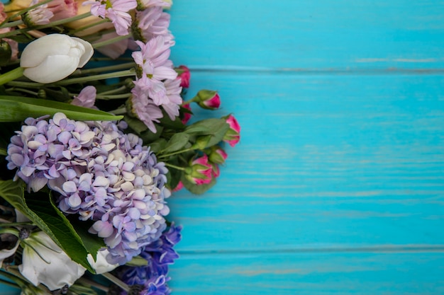 Top view of wonderful colorful flowers like gardenzia rose tulip with leaves on a blue background with copy space