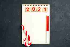 Free photo top view wood block red marker xmas candy on notebook on dark background free space