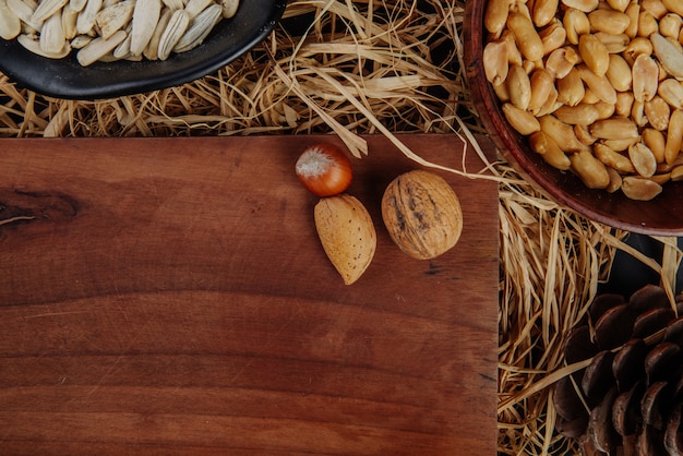 Top view of a wood board with nuts and beer snacks on straw 