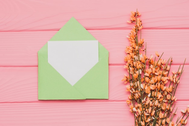 Top view of wooden background with blank note and flowers