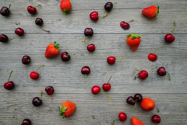 Top view of wooden background with cherries and strawberries