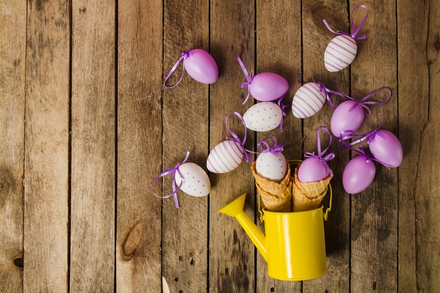Top view of wooden background with watering can and easter eggs
