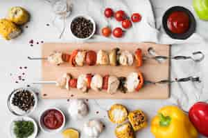 Free photo top view wooden board with grilled chicken and vegetables skewers