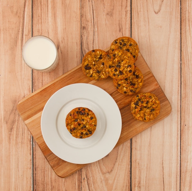 Top view of a wooden board with pumpkin and oatmeal muffins and milk