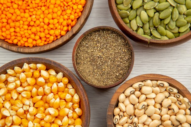 Top view wooden bowls with corn seeds black-eyed peas pumpkin seeds lentiles black pepper bowl