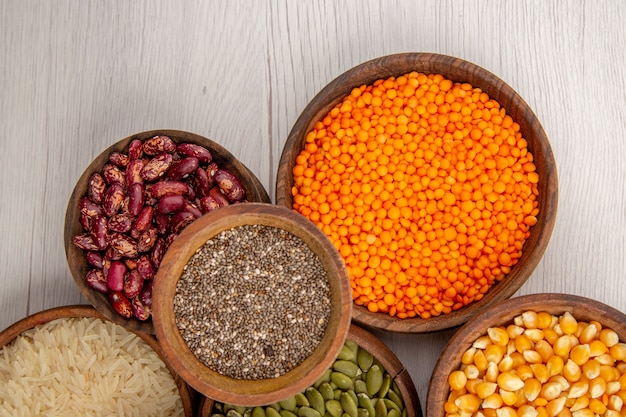 Free photo top view wooden bowls with rice black pepper lentiles pumpkin seeds on wooden table