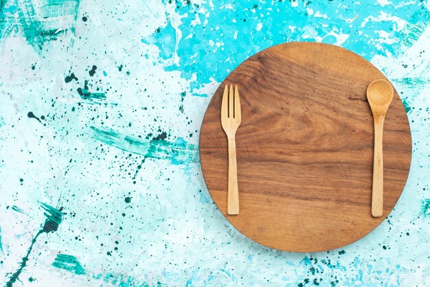 Top view wooden cutlery forks and spoon on the light-blue background spoon wood light color