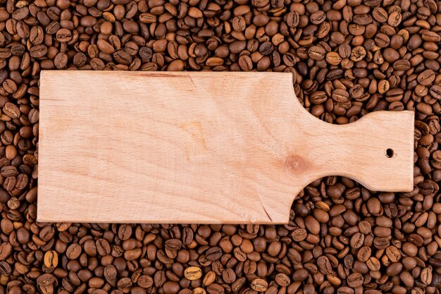 Top view wooden cutting board on coffee beans  surface