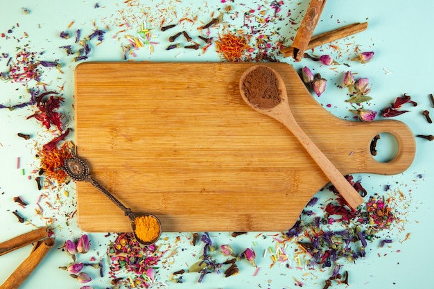 Top view of a wooden cutting board with a spoon of cinnamon powder on blue