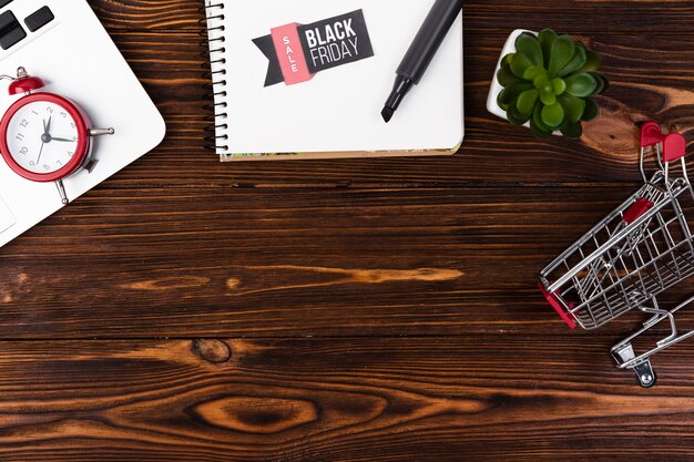 Top view wooden desk with black friday sticker on notepad