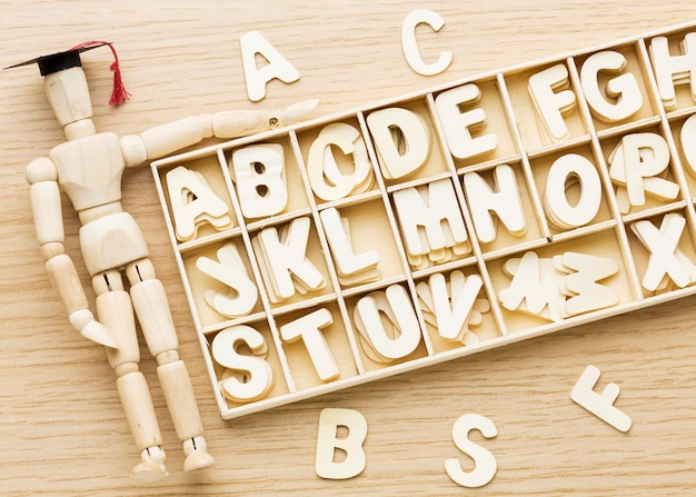 Free photo top view of wooden figurine with academic cap and letters