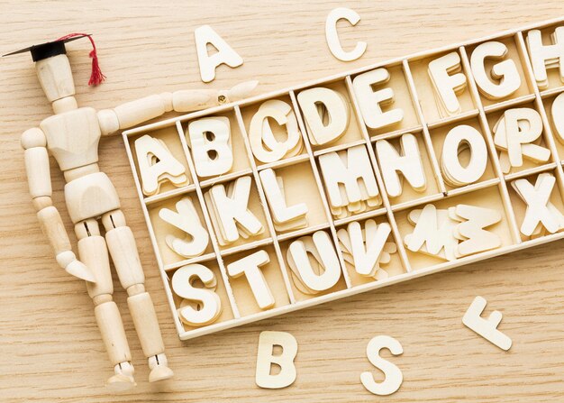 Top view of wooden figurine with academic cap and letters