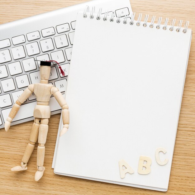 Top view of wooden figurine with academic cap and notebook