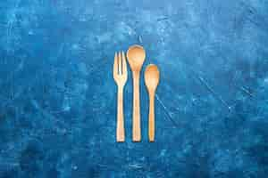 Free photo top view wooden fork spoon knife on blue table with free place