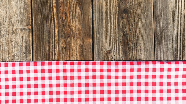 Top view of wooden plank and checkered tablecloth