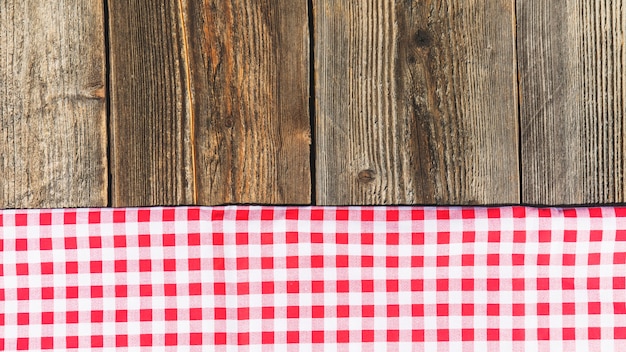 Top view of wooden plank and checkered tablecloth