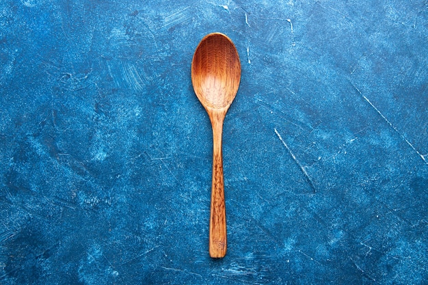 Top view wooden spoon on blue table copy place