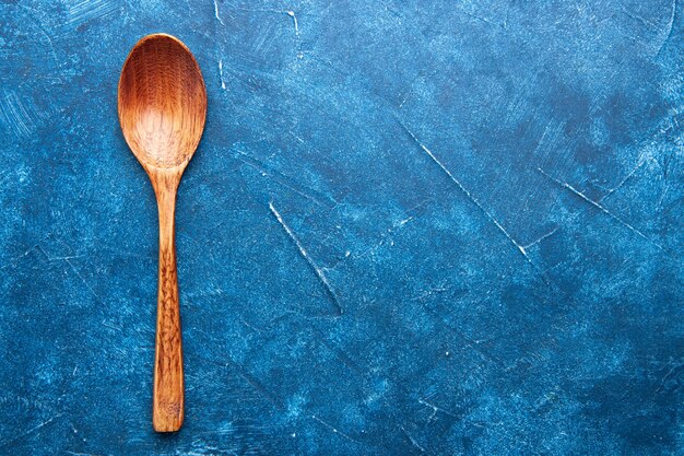 Top view wooden spoon on blue table free place