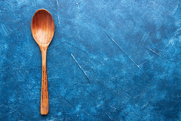 Top view wooden spoon on blue table free place
